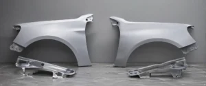 Peças de lataria automotiva lado a lado em ambiente industrial, comparando qualidade e acabamento entre peças originais de montadora e peças OEM, com destaque para encaixe e estrutura metálica.