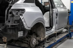 Veículo em oficina de funilaria durante reparação da lateral automotiva, com substituição da lataria e preparação para pintura, destacando o processo de recuperação estrutural da carroceria.